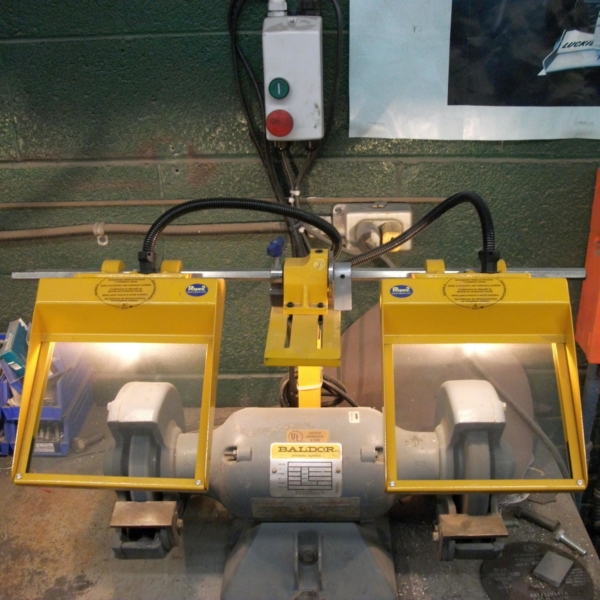 Safety guard installed on a bench grinder with illumination