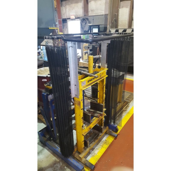A hydraulic press with a steel mesh safety curtain installed for protection against ejections. The curtain is open in this image.
