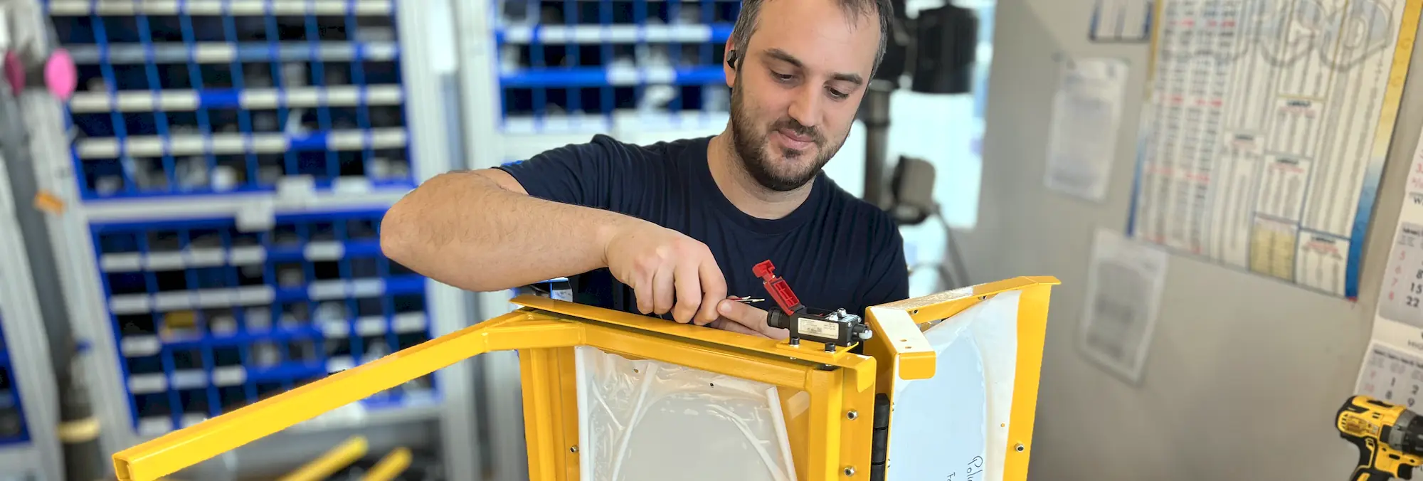 A machine safety technician installing a safety interlock switch on a safety guard