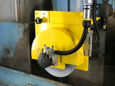An automated grinding wheel guard installed on a surface grinder.
