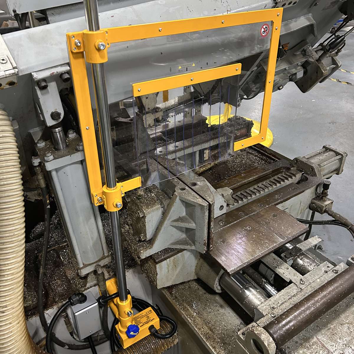 A Horizontal band saw safety guard installed on a machine.
