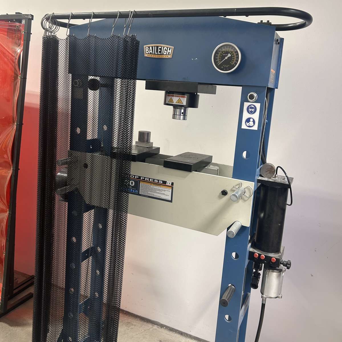 A hydraulic H-frame press with a steel mesh ejection curtain installed on it for protection by Ferndale Safety.