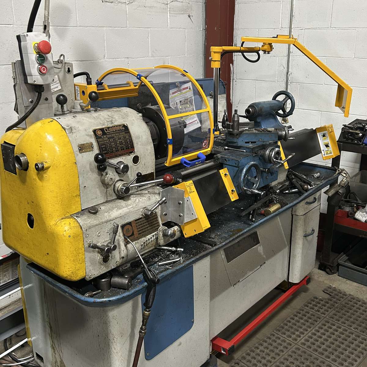 A photo of a lathe that has a full lathe-safety-guarding-bundle installed, including a chuck guard, lead screw cover, chip shield, and stop pedal.