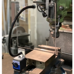 Un garde en polycarbonate est placé devant la broche d'une fraiseuse. Le garde est maintenu par un flexible fixé à une base magnétique qui adhère à l'étau. 