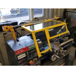 A small hobby workshop lathe with a safety guard installed over top of it.